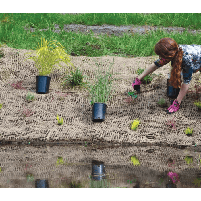 jute erosion control fabric with plants in pots and planted in fabric woman planting with red hair
